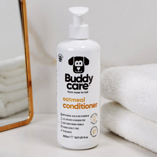 Buddy Care oatmeal conditioner bottle on a white surface with towels in the background